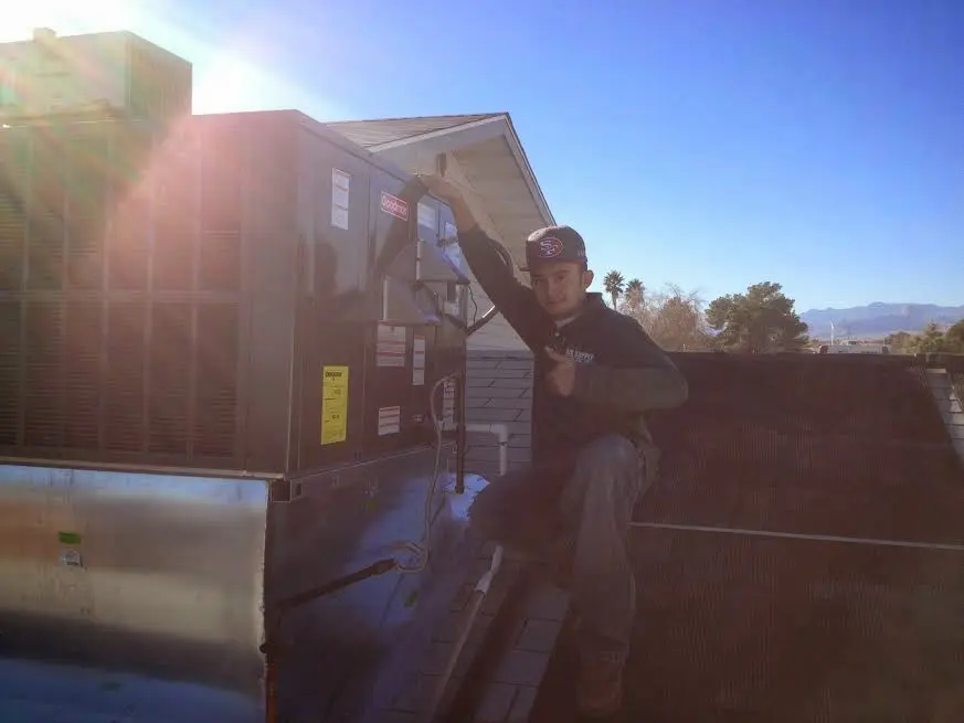 HVAC technician performing Air Duct Cleaning on a rooftop unit in Staunton